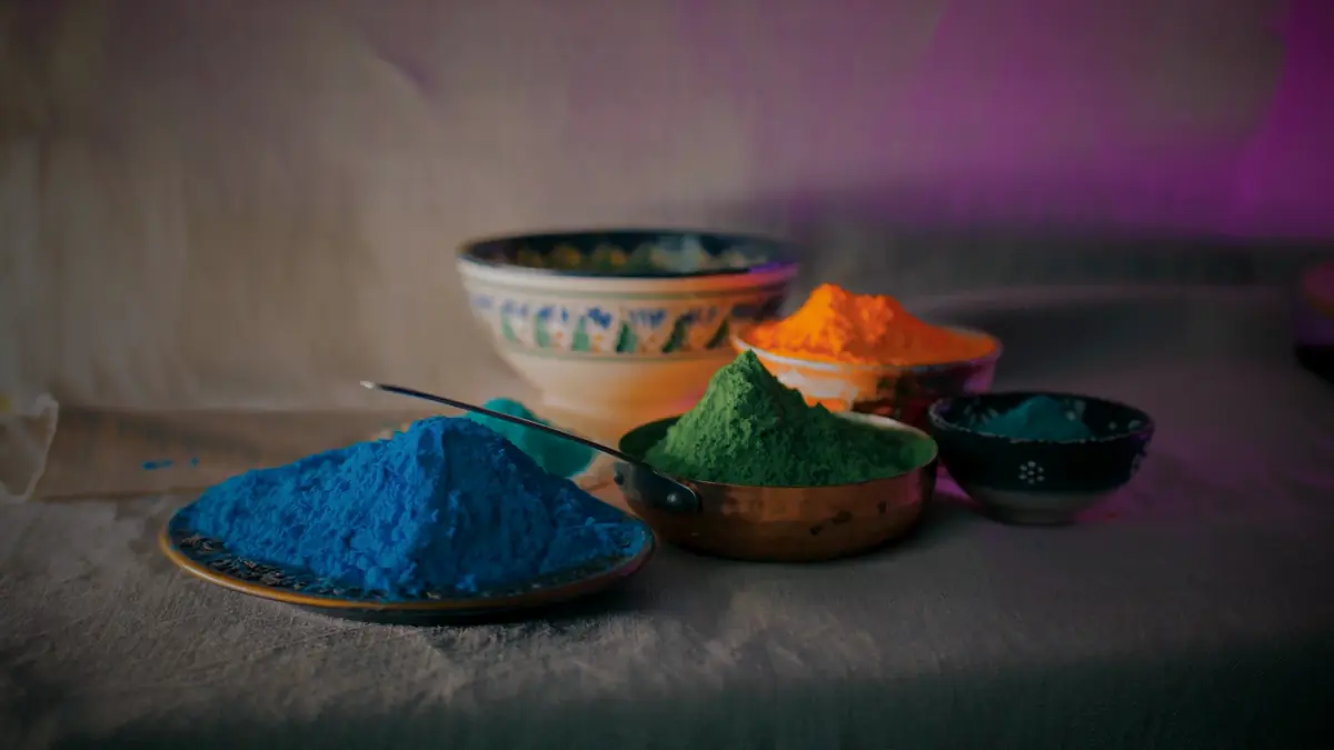 Bowls of bright blue, green, orange and teal colored powder